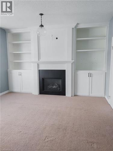 Built-in white cabinetry and shelving flanking a black-framed fireplace with a classic mantelpiece - 569 Activa Avenue, Kitchener, ON - Indoor Photo Showing Living Room With Fireplace