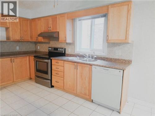 Kitchen featuring light wood cabinetry, stone-look countertops, and a tiled backsplash - 569 Activa Avenue, Kitchener, ON - Indoor Photo Showing Kitchen With Double Sink