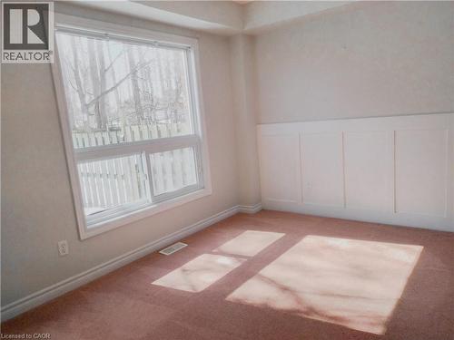 Spacious room featuring a large window, board and batten wall detailing, light-colored walls, base molding, and carpet flooring - 569 Activa Avenue, Kitchener, ON - Indoor Photo Showing Other Room