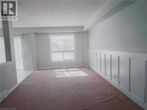 Carpeted living area with wainscoting detail and a large window providing ample natural light - 569 Activa Avenue, Kitchener, ON - Indoor Photo Showing Other Room