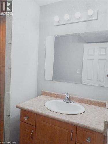 Bathroom vanity with a light wood-finish cabinet, integrated oval sink, and a speckled countertop - 569 Activa Avenue, Kitchener, ON - Indoor Photo Showing Bathroom