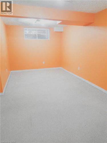 Spacious room featuring light orange walls, white trim, and light-colored carpeting - 569 Activa Avenue, Kitchener, ON - Indoor