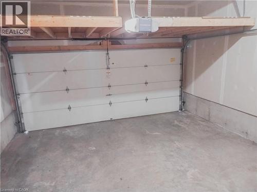 Interior garage space featuring a white sectional garage door, concrete flooring, and an overhead storage platform - 569 Activa Avenue, Kitchener, ON - Indoor Photo Showing Garage