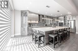 Kitchen featuring decorative light fixtures, modern cabinets, wall chimney range hood, appliances with stainless steel finishes, and decorative backsplash - 