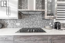 Kitchen featuring decorative backsplash, wall chimney exhaust hood, black electric stovetop, and modern cabinets - 