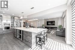 Kitchen featuring modern cabinets, a breakfast bar, stainless steel refrigerator with ice dispenser, a tiled fireplace, and light wood finished floors - 