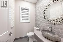 Half bathroom with baseboards, an accent wall, tile walls, toilet, and tile patterned floors - 