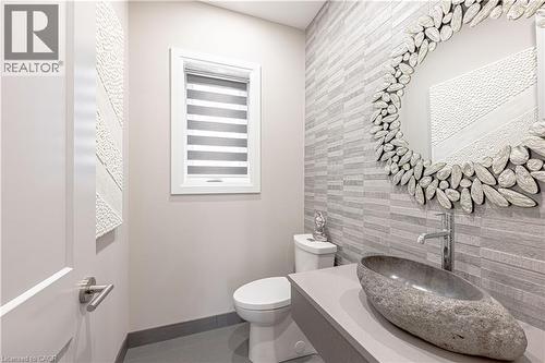 Half bathroom with baseboards, an accent wall, tile walls, toilet, and tile patterned floors - 477 Blair Creek Drive, Kitchener, ON - Indoor Photo Showing Bathroom