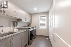 Clothes washing area featuring baseboards, light tile patterned floors, independent washer and dryer, cabinet space, and a sink - 