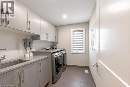 Clothes washing area featuring baseboards, light tile patterned floors, independent washer and dryer, cabinet space, and a sink - 477 Blair Creek Drive, Kitchener, ON - Indoor Photo Showing Laundry Room