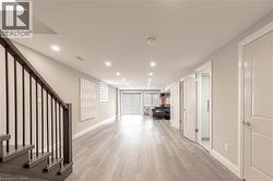 Hallway featuring light wood-style floors, baseboards, stairs, and recessed lighting - 