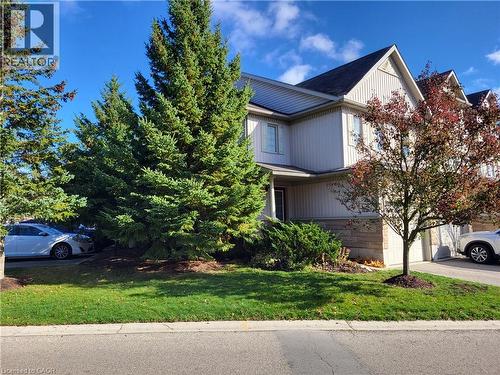 View of front facade featuring stone siding, driveway, a garage, and a front yard - 85 Bankside Drive Unit# E34, Kitchener, ON - Outdoor