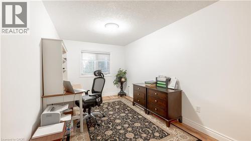 Home office featuring light wood-style flooring, baseboards, and a textured ceiling - 85 Bankside Drive Unit# E34, Kitchener, ON - Indoor