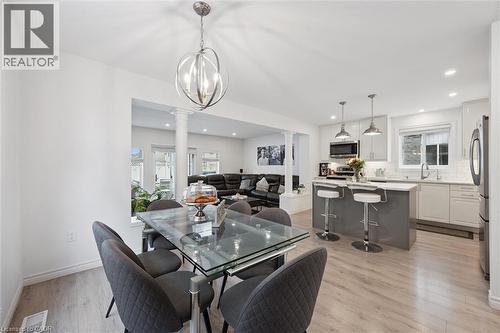 Bright kitchen and dining area featuring light wood-finish flooring, white cabinetry, a kitchen island with seating, a stainless steel refrigerator, and recessed lighting - 11 Patton Drive, Cambridge, ON - Indoor Photo Showing Other Room