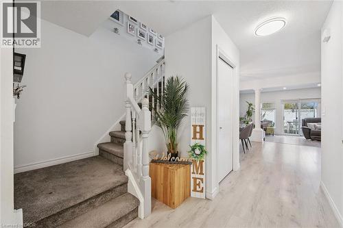 Entryway featuring light wood-finish flooring, a carpeted staircase with white balusters, and a contemporary flush-mount ceiling light - 11 Patton Drive, Cambridge, ON - Indoor Photo Showing Other Room