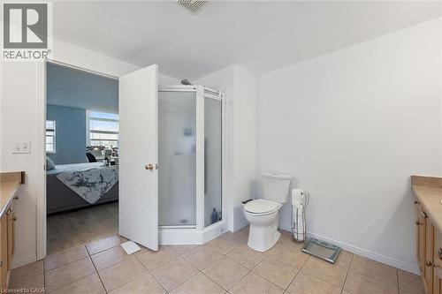 Bathroom featuring a corner shower enclosure, standard toilet, and dual vanity areas with wood cabinetry and light-toned countertops - 11 Patton Drive, Cambridge, ON - Indoor Photo Showing Bathroom
