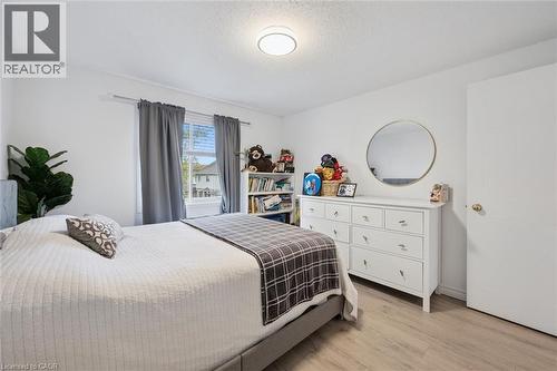 Light-filled room featuring a window with natural light, wood-finish flooring, a contemporary ceiling light fixture, and white wall paint - 11 Patton Drive, Cambridge, ON - Indoor Photo Showing Bedroom