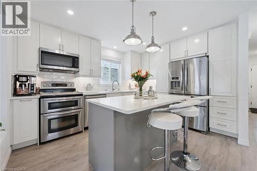 Modern kitchen featuring white cabinetry, stainless steel appliances, a center island with countertop seating, wood-finish flooring, and pendant lighting - 11 Patton Drive, Cambridge, ON - Indoor Photo Showing Kitchen With Stainless Steel Kitchen With Upgraded Kitchen
