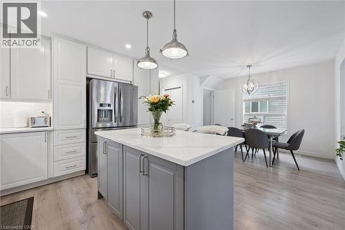 Kitchen featuring a central island with a light countertop, pendant lighting, white upper and lower cabinetry, stainless steel appliances, and wood-finish flooring - 11 Patton Drive, Cambridge, ON - Indoor Photo Showing Other Room
