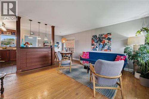 Hardwood flooring throughout the living area, featuring a decorative half-wall with wood pillars and three pendant lights over a breakfast bar - 154 Oriole Street, Waterloo, ON - Indoor