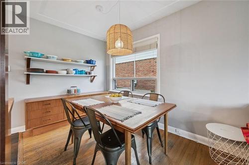 Dining area featuring wood-finish flooring, a wood-finish dining table, built-in shelving, a full-lite window, and a woven pendant light fixture - 154 Oriole Street, Waterloo, ON - Indoor Photo Showing Dining Room