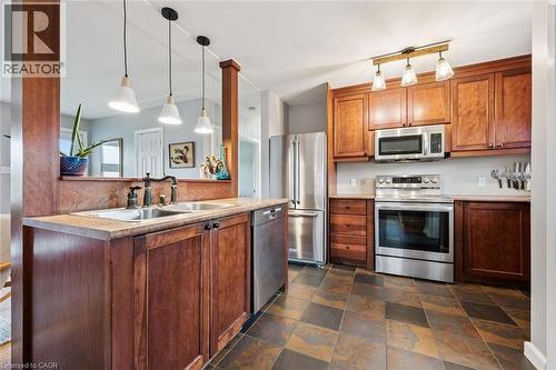 Kitchen featuring stainless steel appliances, rich wood cabinetry, a double basin sink, stone-look countertops, and multi-toned tile flooring - 154 Oriole Street, Waterloo, ON - Indoor Photo Showing Kitchen With Stainless Steel Kitchen With Double Sink