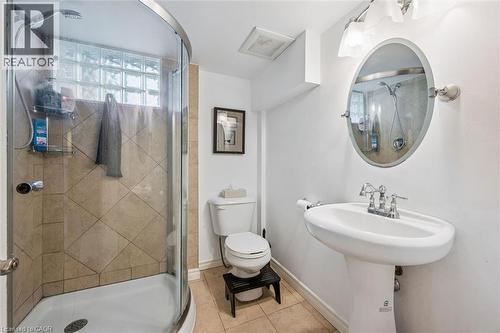 Bathroom featuring a corner shower with glass enclosure and tile surround, a pedestal sink, and an oval mirror with wall sconce lighting - 154 Oriole Street, Waterloo, ON - Indoor Photo Showing Bathroom