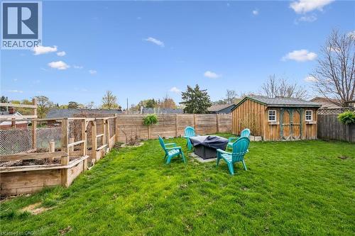 Expansive fenced backyard featuring a manicured lawn, dedicated garden beds, a wooden storage shed, and a paved patio area - 154 Oriole Street, Waterloo, ON - Outdoor