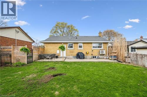 Expansive grassy backyard featuring a concrete patio, brick exterior, and a privacy fence - 154 Oriole Street, Waterloo, ON - Outdoor