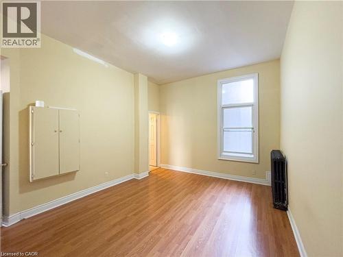 Room featuring wood-finish flooring, light-toned wall paint, and white baseboards - 85 King Street W, Kitchener, ON 