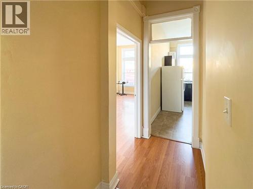 Hallway with wood-finish flooring and light yellow walls - 85 King Street W, Kitchener, ON 