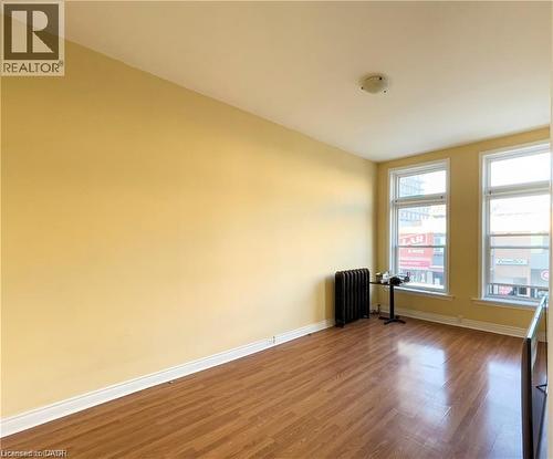 Room featuring wood-finish flooring, light-colored walls, and a white ceiling with a flush-mount light fixture - 85 King Street W, Kitchener, ON 