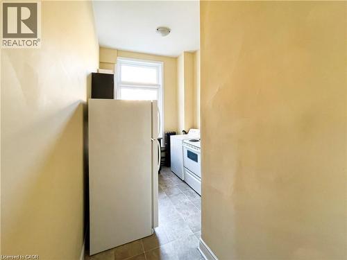 Kitchen area featuring a window, tile flooring, and light-colored walls - 85 King Street W, Kitchener, ON 