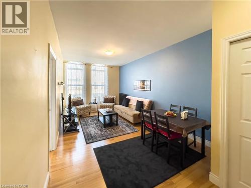 Open-concept living and dining area featuring wood-finish flooring, recessed lighting, and a neutral color palette - 85 King Street W, Kitchener, ON 