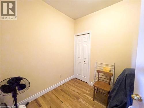 Room featuring wood-finish flooring, light-toned wall paint, white baseboards, and a white bi-fold closet door - 85 King Street W, Kitchener, ON 