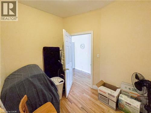 Interior space featuring wood-finish flooring, a white paneled door, and light-toned wall finishes - 85 King Street W, Kitchener, ON 