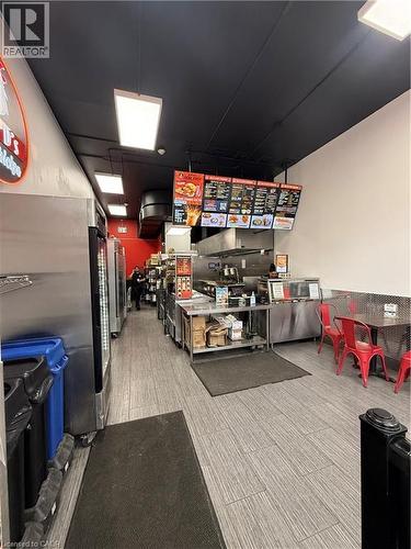 Commercial kitchen featuring stainless steel equipment, tile flooring, and track lighting - 85 King Street W, Kitchener, ON 