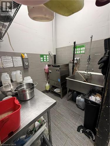 Stainless steel commercial kitchen area featuring a large sink basin, a commercial dishwasher, and a stainless steel prep table - 85 King Street W, Kitchener, ON 
