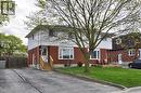Two-story residence featuring a brick and white siding exterior, a front entry with wooden steps and railing, a front yard with a mature tree and green lawn, a wooden deck, and an asphalt driveway - 114 Bakersfield Drive, Cambridge, ON  - Outdoor 