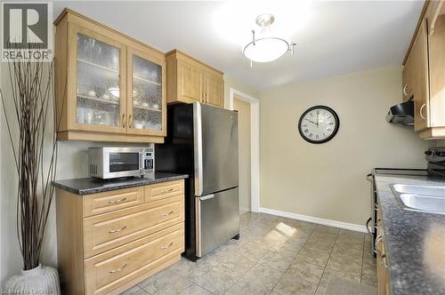 Kitchen featuring light wood cabinetry, a stainless steel refrigerator, dark speckled countertops, and tiled flooring - 114 Bakersfield Drive, Cambridge, ON - Indoor Photo Showing Kitchen With Double Sink