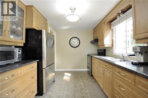 Kitchen featuring light wood cabinetry with brushed nickel hardware, dark speckled countertops, and tile flooring - 114 Bakersfield Drive, Cambridge, ON - Indoor Photo Showing Kitchen With Double Sink