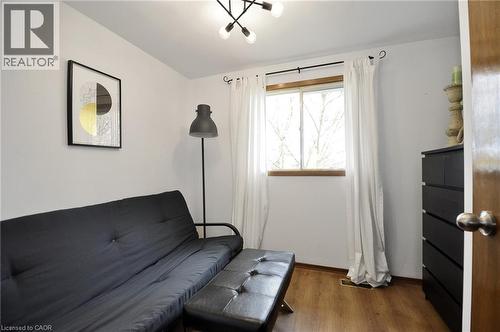 Light-filled room featuring wood-finish flooring, a contemporary ceiling light fixture, a window with a wood trim, white walls, and a wood-paneled door - 114 Bakersfield Drive, Cambridge, ON - Indoor