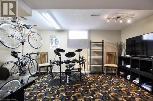 Spacious room with a neutral wall color, patterned carpet flooring, and a large window providing natural light - 114 Bakersfield Drive, Cambridge, ON - Indoor Photo Showing Other Room