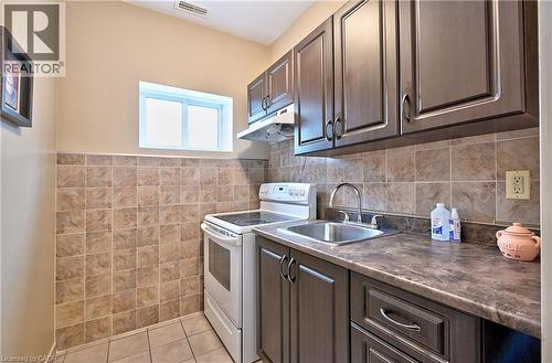 Kitchen area featuring dark wood-finish cabinetry, a stainless steel sink with a chrome faucet, and a stone-look countertop - 1476 Barton Street E, Hamilton, ON - Indoor Photo Showing Kitchen