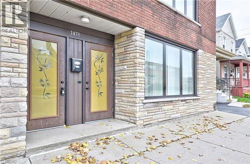 Front facade with brick and stone veneer, featuring dual entry doors with decorative glass panels and a large multi-pane window - 1476 Barton Street E, Hamilton, ON - Outdoor
