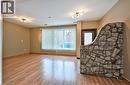 Interior space with wood-finish flooring, a prominent stone partition wall, and vertical blinds covering a large window - 1476 Barton Street E, Hamilton, ON  - Indoor Photo Showing Other Room 