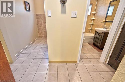Tile flooring throughout, featuring a bathroom with a vanity sink, mirror, and bathtub with tiled surround - 1476 Barton Street E, Hamilton, ON - Indoor