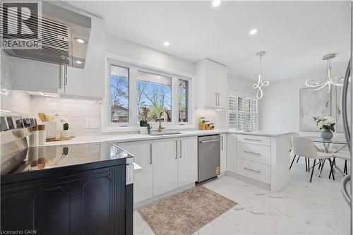 Contemporary kitchen featuring white cabinetry, integrated stainless steel appliances, a large window over the sink, recessed lighting, and tile flooring - 111 Ruskview Road, Kitchener, ON - Indoor Photo Showing Kitchen With Upgraded Kitchen