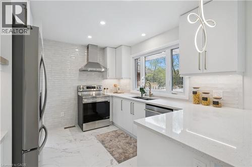Modern kitchen featuring white cabinetry, light-colored countertops, stainless steel appliances, a large window, and recessed lighting with a decorative pendant fixture - 111 Ruskview Road, Kitchener, ON - Indoor Photo Showing Kitchen With Stainless Steel Kitchen With Double Sink With Upgraded Kitchen