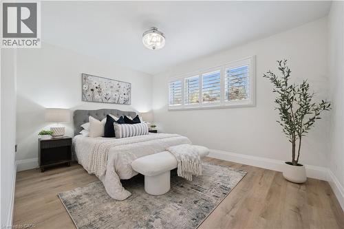 Light-filled room featuring wide-plank wood-finish flooring, white walls, and a contemporary semi-flushmount ceiling fixture - 111 Ruskview Road, Kitchener, ON - Indoor Photo Showing Bedroom